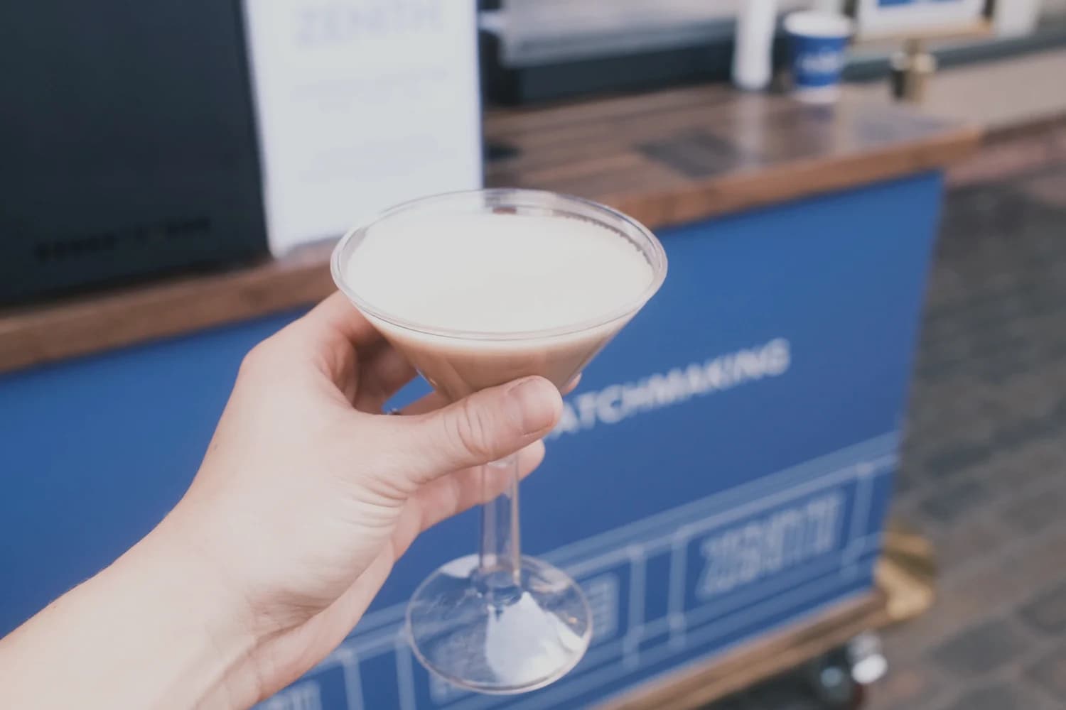 Espresso mocktini held in front of the ZENITH-wrapped Flipside cart
