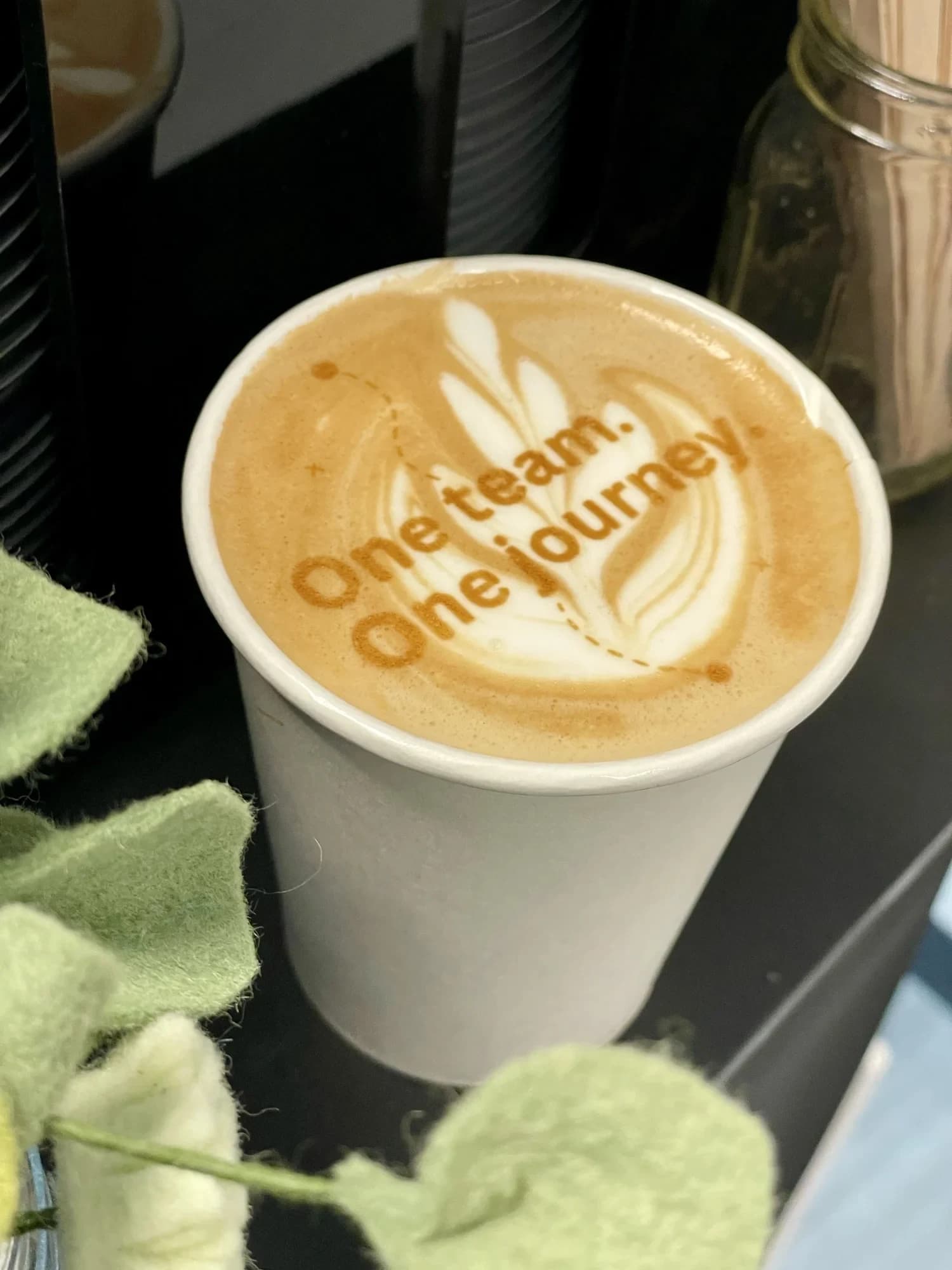 Latte with 'One team. One journey.' printed in the foam