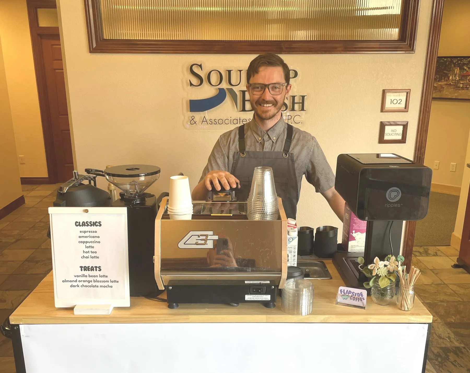 Flipside barista smiling behind a mobile espresso cart at an office event