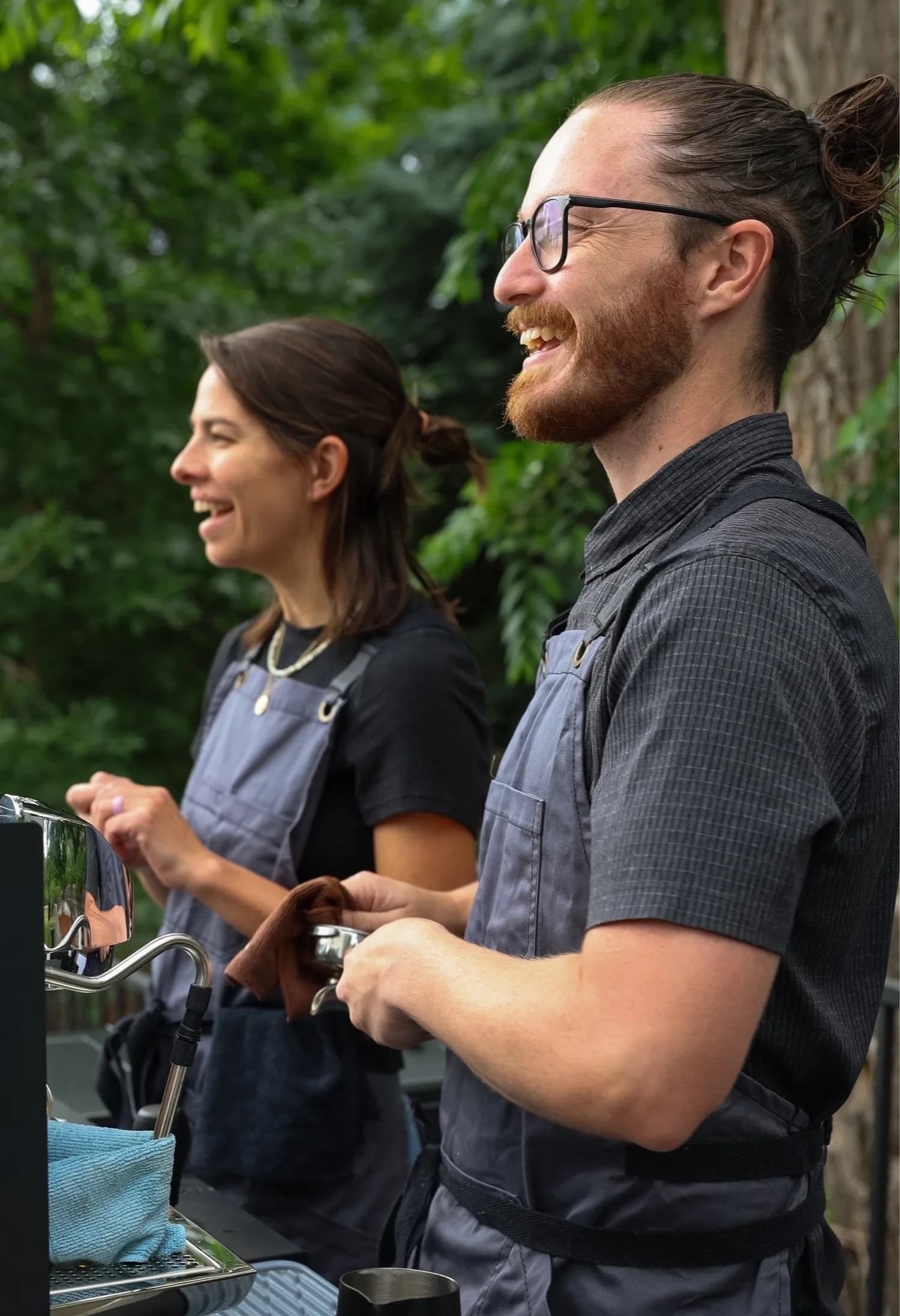 Two Flipside baristas laughing at the espresso machine at an outdoor event